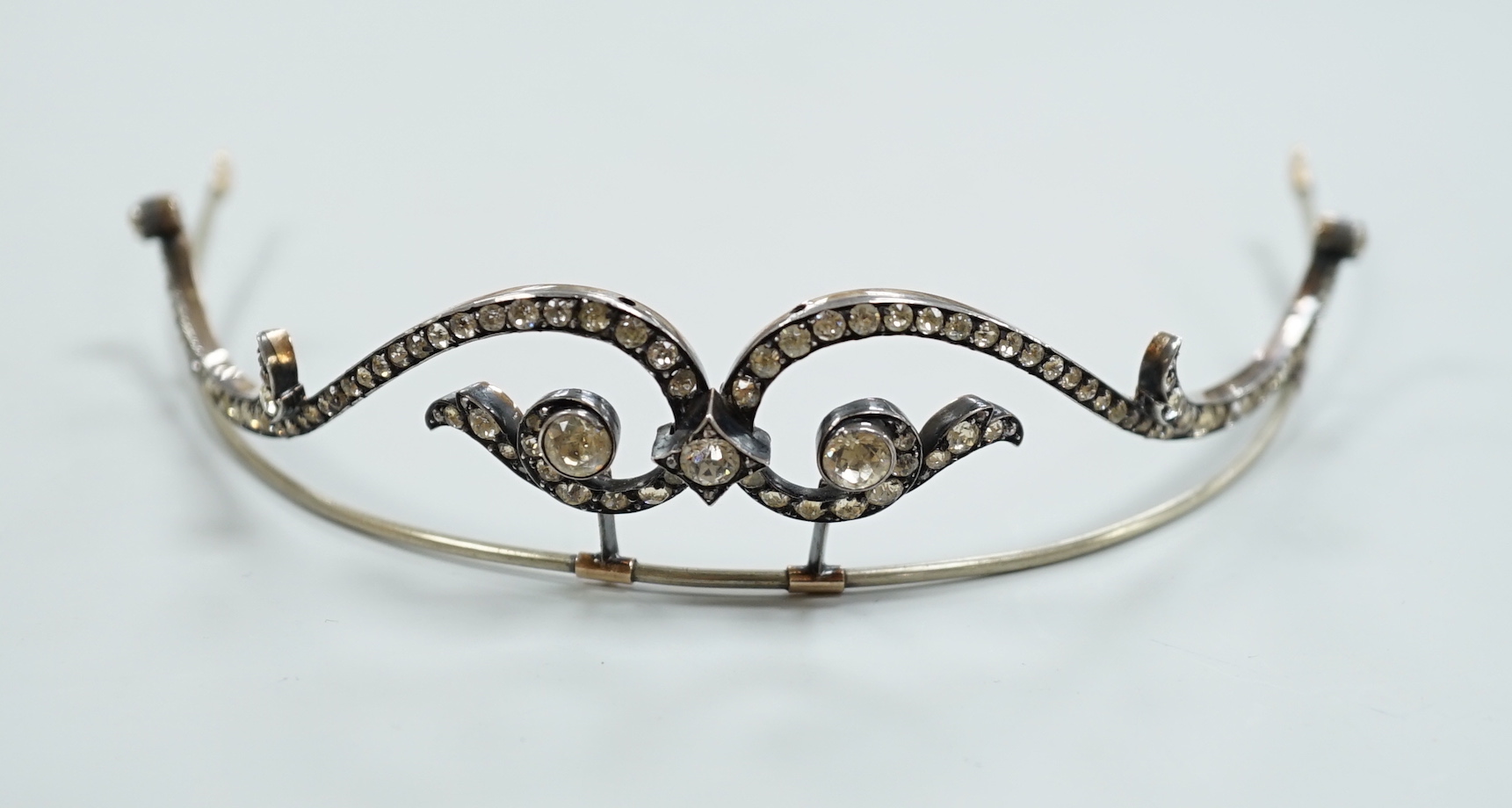 A 19th century, white and yellow metal paste cluster set tiara, width 13cm, the central stone with rose cut diamond chip spacers.